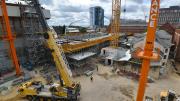 "Yellow crane with six wheels in the foreground of construction." 